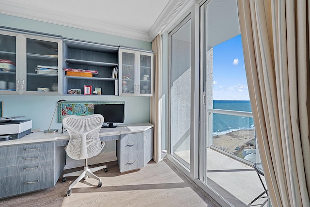 home office with light wood-type flooring, crown molding, and built in study area