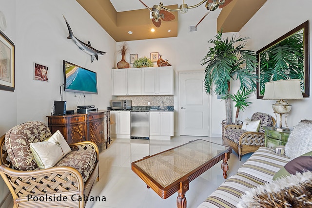 living area with a towering ceiling, ceiling fan, visible vents, and light tile patterned flooring