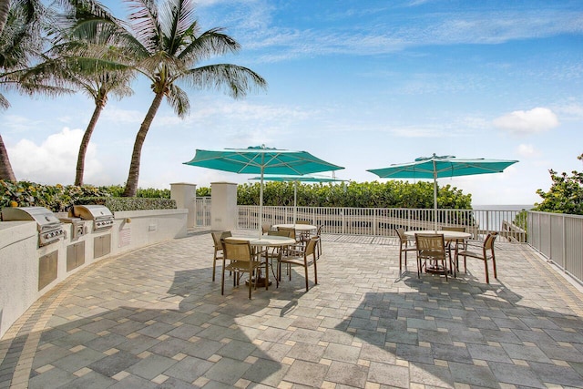 view of patio featuring outdoor dining area, a grill, an outdoor kitchen, and fence