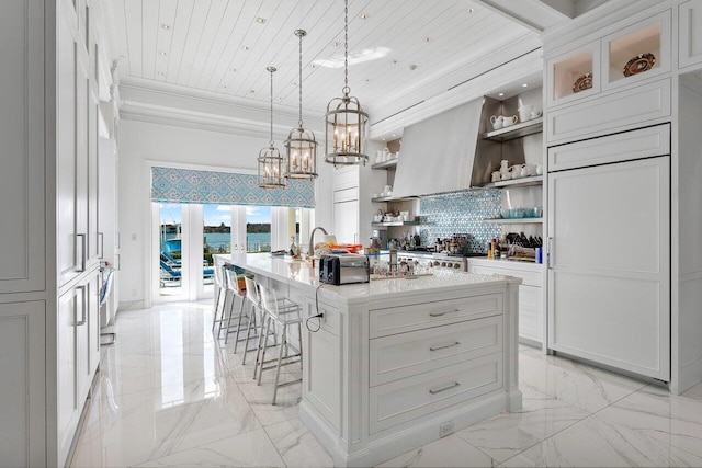 kitchen featuring white cabinets, an island with sink, wood ceiling, and decorative light fixtures