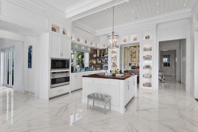 kitchen with wooden counters, decorative light fixtures, white cabinets, and stainless steel oven