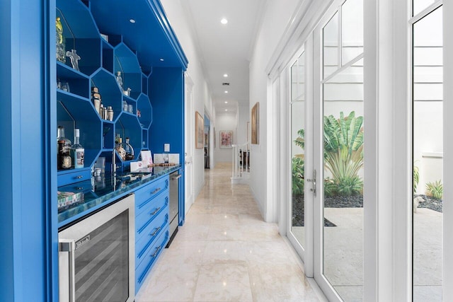 bar with plenty of natural light, blue cabinets, and beverage cooler