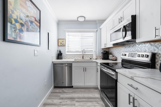 kitchen with sink, light hardwood / wood-style floors, decorative backsplash, white cabinets, and appliances with stainless steel finishes