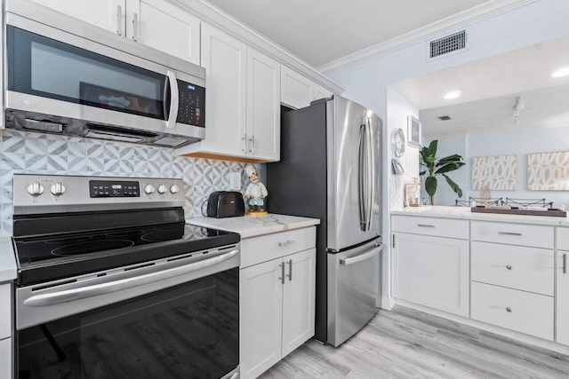 kitchen featuring white cabinets, appliances with stainless steel finishes, light hardwood / wood-style flooring, and ornamental molding