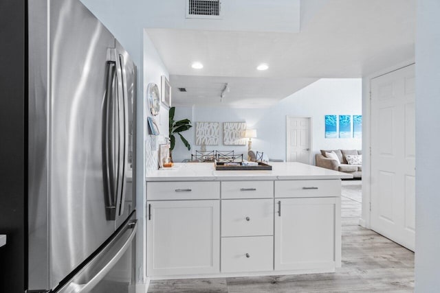 kitchen featuring stainless steel refrigerator, white cabinetry, and light wood-type flooring