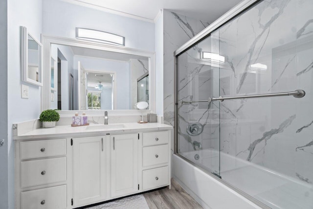 bathroom with crown molding, vanity, enclosed tub / shower combo, and wood-type flooring