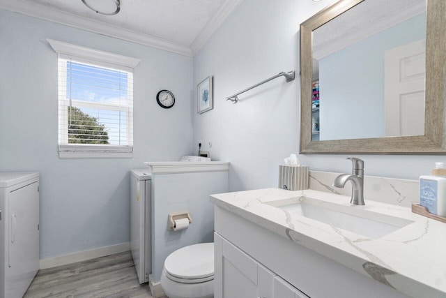 bathroom featuring wood-type flooring, a textured ceiling, washer and clothes dryer, vanity, and ornamental molding