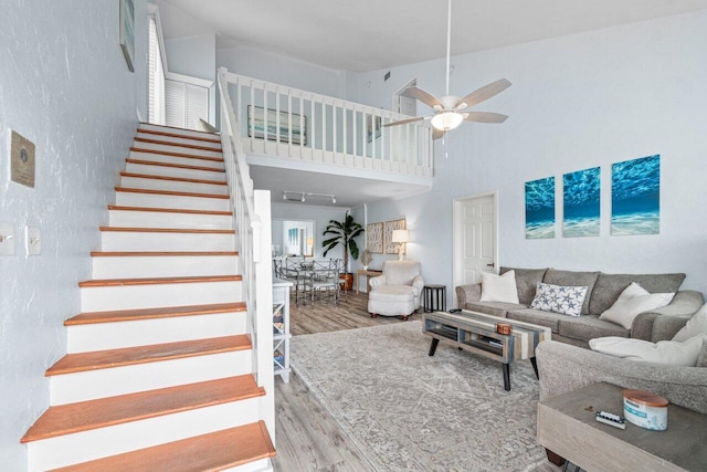 living room featuring ceiling fan, wood-type flooring, and a high ceiling