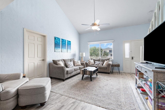 living room with ceiling fan, light hardwood / wood-style flooring, and high vaulted ceiling