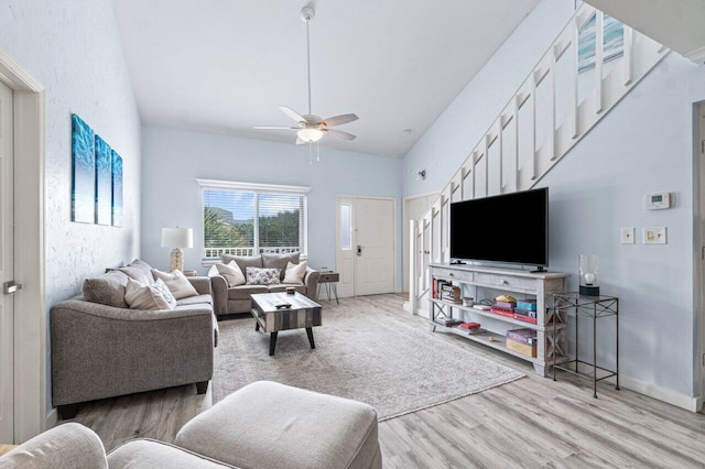 living room with hardwood / wood-style floors, ceiling fan, and high vaulted ceiling