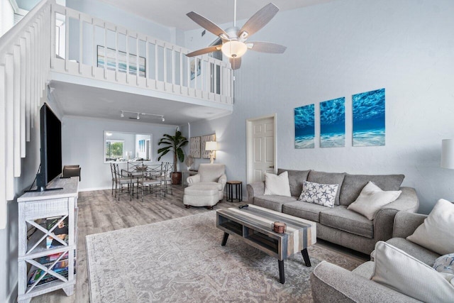 living room featuring ceiling fan, wood-type flooring, and a high ceiling