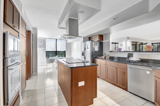 kitchen with a textured ceiling, a kitchen island, light tile patterned floors, and appliances with stainless steel finishes