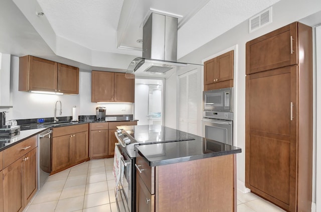 kitchen featuring a center island, sink, light tile patterned floors, a textured ceiling, and stainless steel appliances