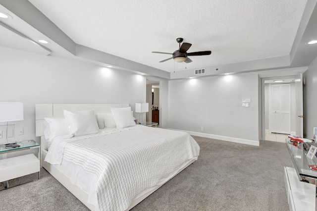 bedroom with ceiling fan, light colored carpet, and a textured ceiling