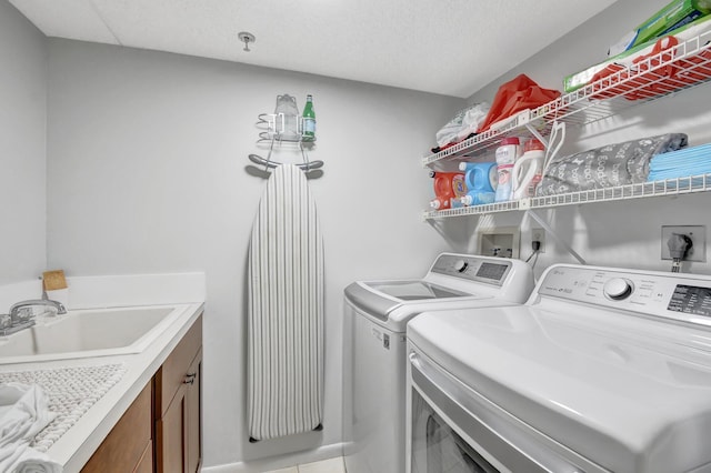 washroom featuring sink, cabinets, a textured ceiling, washer and clothes dryer, and light tile patterned floors