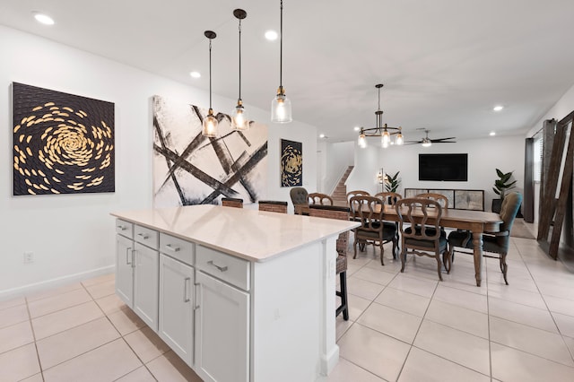 kitchen with a breakfast bar, a kitchen island, ceiling fan, decorative light fixtures, and white cabinetry