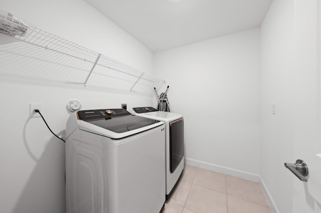 clothes washing area featuring washer and clothes dryer and light tile patterned floors