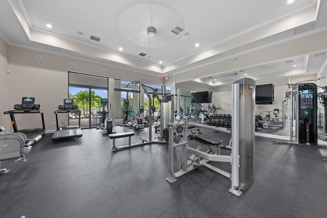 workout area with a tray ceiling, crown molding, and ceiling fan