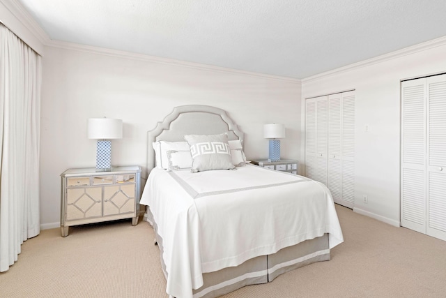 bedroom with ornamental molding, carpet, baseboards, and two closets