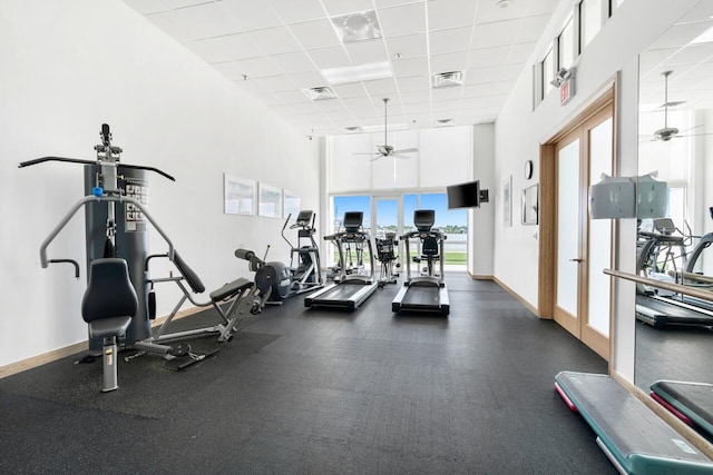 gym with ceiling fan, a drop ceiling, a high ceiling, and a wealth of natural light