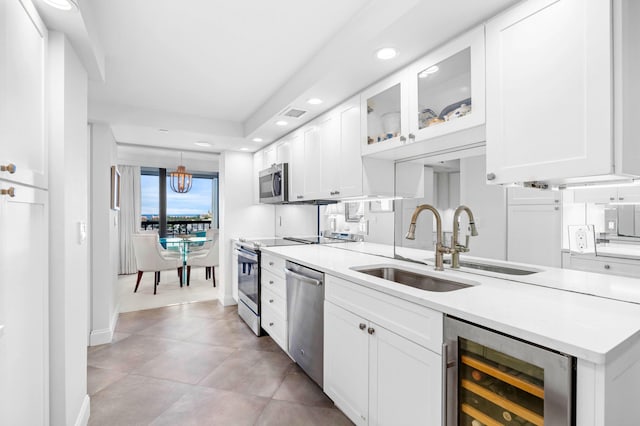 kitchen with stainless steel appliances, wine cooler, white cabinets, and a sink