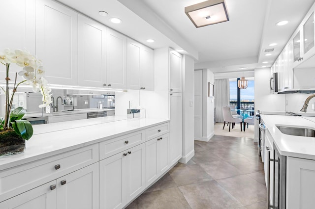 kitchen with light countertops, recessed lighting, a sink, and white cabinets