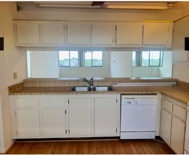 kitchen with white dishwasher, white cabinets, sink, and hardwood / wood-style floors