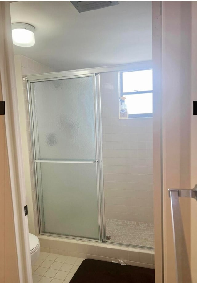 bathroom with tile patterned floors, a shower with shower door, and toilet