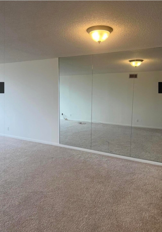 carpeted spare room with a textured ceiling