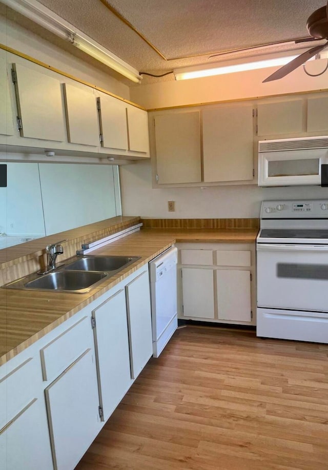 kitchen featuring white cabinets, a textured ceiling, white appliances, and sink