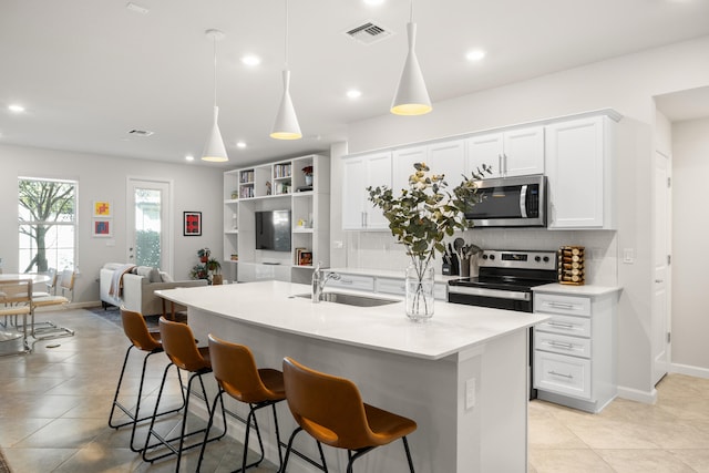 kitchen featuring sink, backsplash, an island with sink, pendant lighting, and appliances with stainless steel finishes