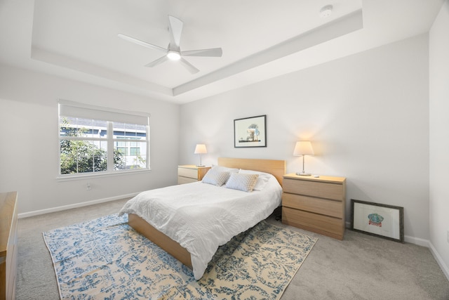 bedroom with light carpet, a raised ceiling, and ceiling fan