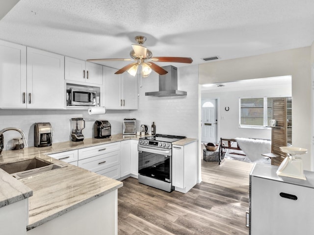 kitchen with wall chimney exhaust hood, stainless steel appliances, sink, light hardwood / wood-style floors, and white cabinetry