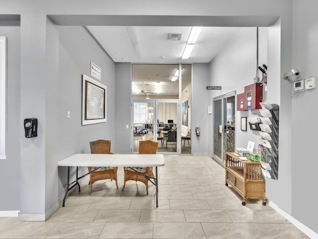 hall with light tile patterned floors and a textured ceiling