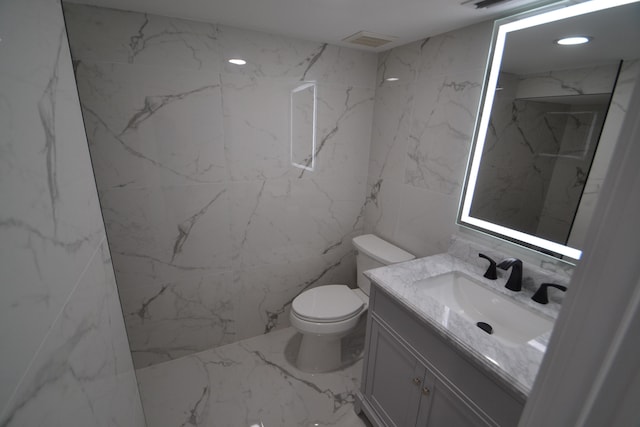 bathroom featuring vanity, toilet, and tile walls