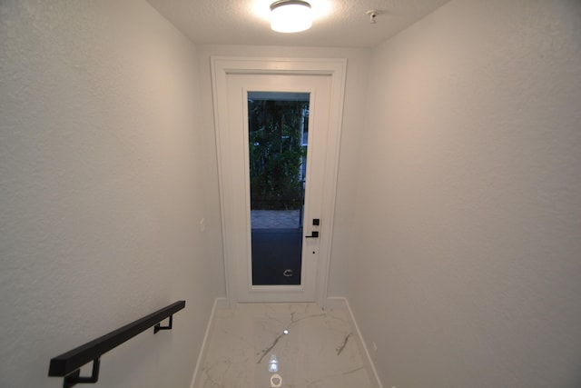 doorway to outside with a textured ceiling