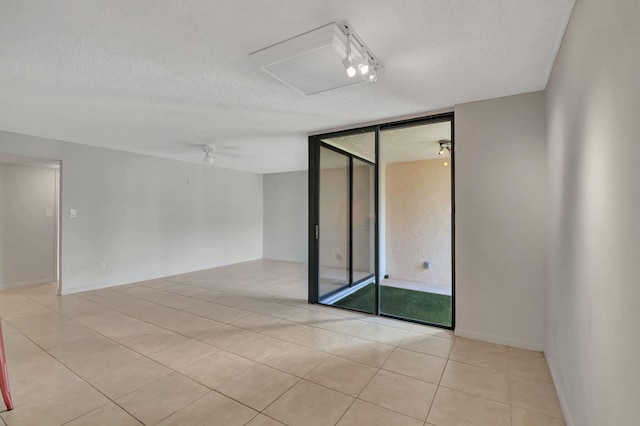 empty room featuring light tile patterned floors, a textured ceiling, and ceiling fan