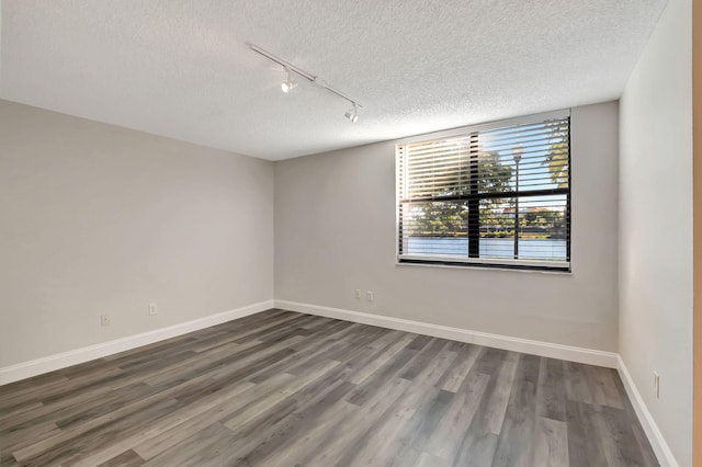 unfurnished room with hardwood / wood-style floors, a textured ceiling, and rail lighting