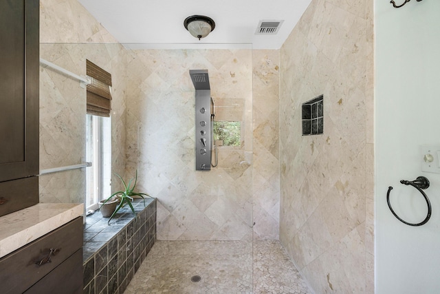 bathroom with a tile shower and visible vents