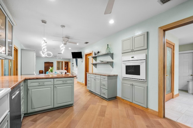 kitchen with white oven, light wood-type flooring, stainless steel dishwasher, and ceiling fan