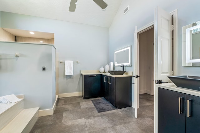 bathroom with a textured ceiling, vaulted ceiling, ceiling fan, and sink