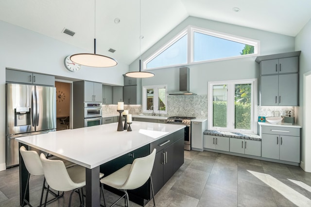 kitchen featuring decorative backsplash, a center island, wall chimney exhaust hood, and appliances with stainless steel finishes