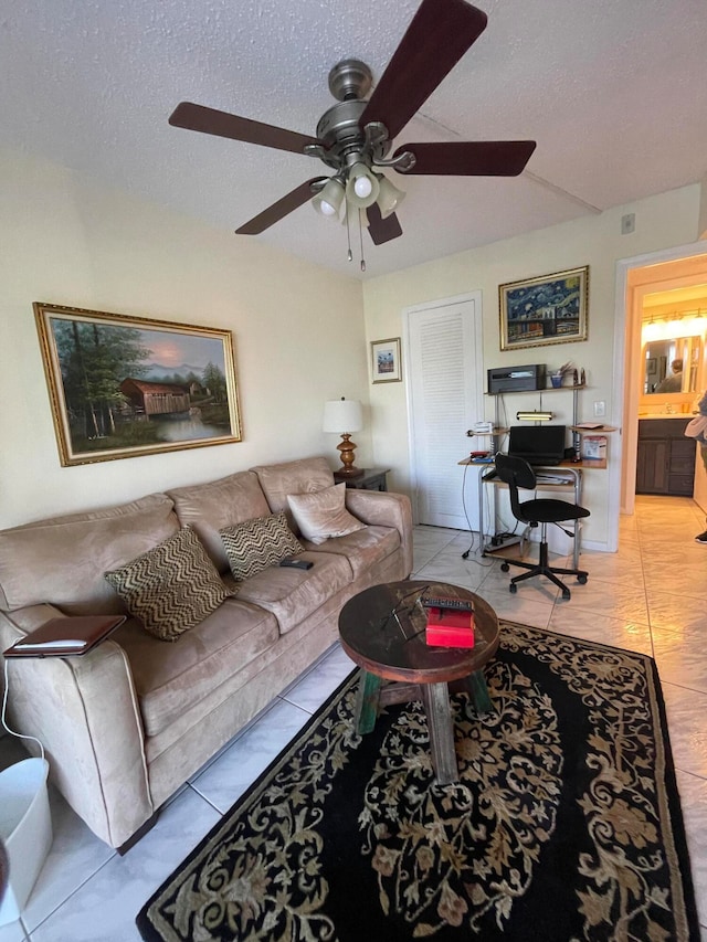 living room with ceiling fan, light tile patterned floors, and a textured ceiling