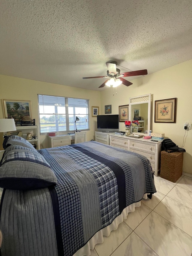 bedroom with ceiling fan, light tile patterned flooring, and a textured ceiling