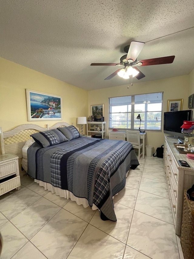 bedroom featuring ceiling fan, light tile patterned floors, and a textured ceiling