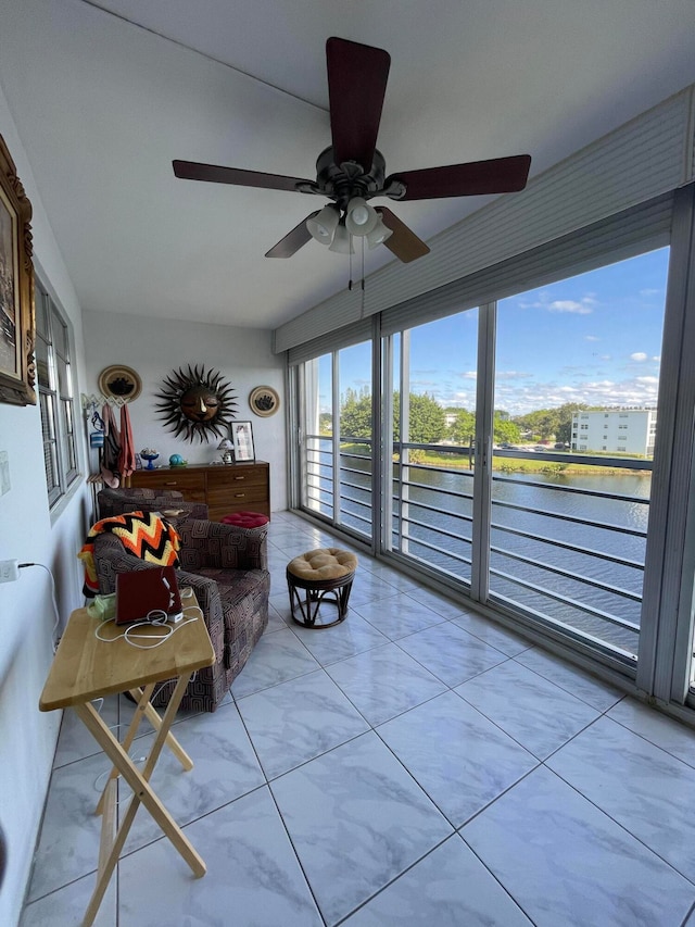 sunroom featuring a water view and ceiling fan