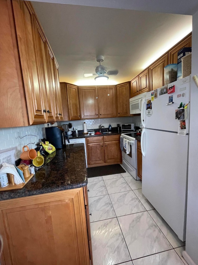 kitchen with white appliances, ceiling fan, dark stone countertops, light tile patterned floors, and tasteful backsplash