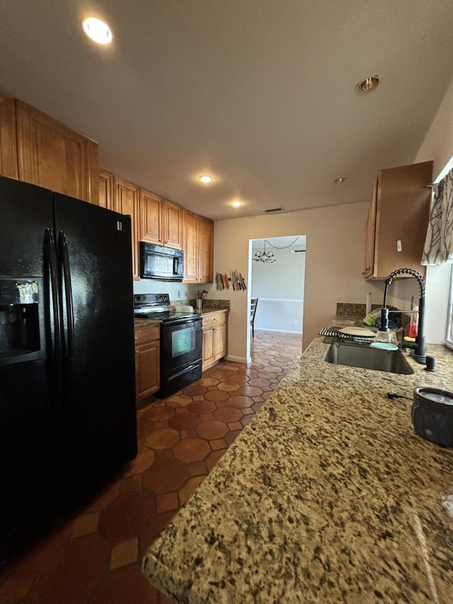 kitchen featuring light stone counters, sink, dark tile patterned floors, and black appliances