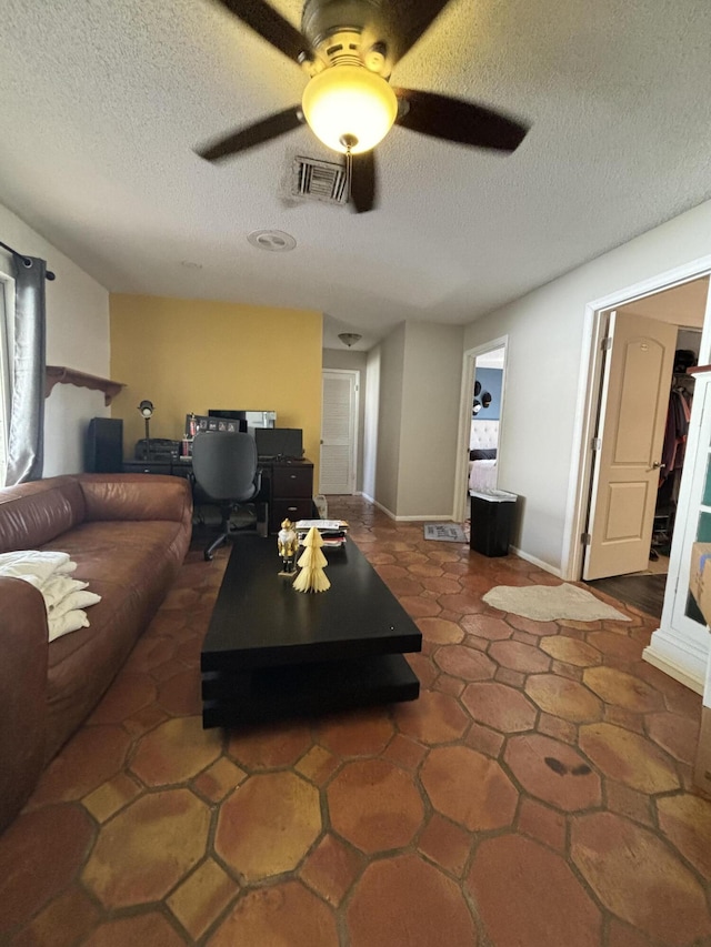 living room featuring ceiling fan and a textured ceiling