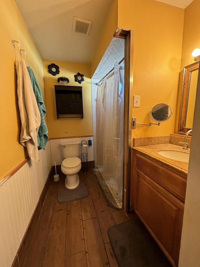 bathroom with hardwood / wood-style floors, vanity, toilet, and walk in shower